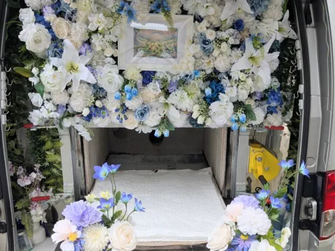 火葬車のお花の祭壇と虹の橋の絵、白い敷布を敷いた火葬炉